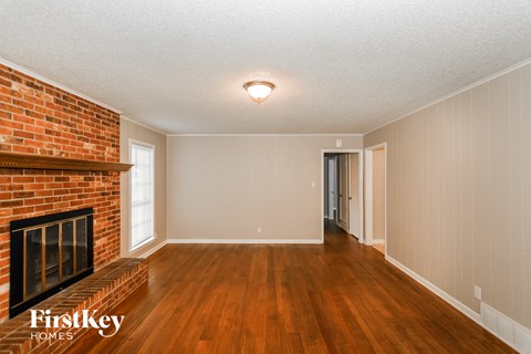 A room with a brick fireplace and wooden floors.