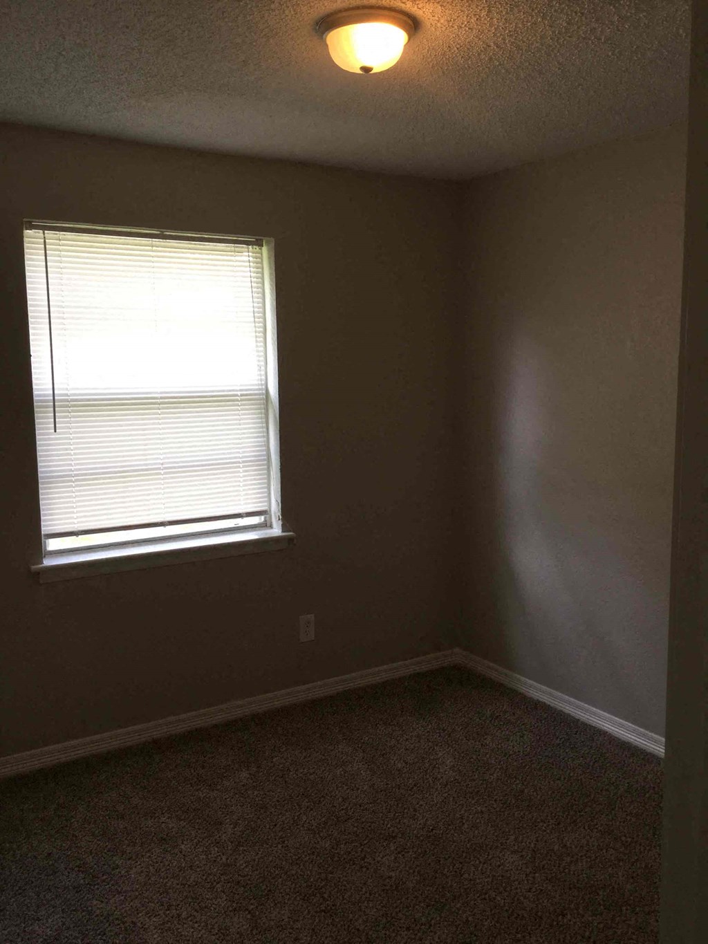 an empty room with a window and a lamp