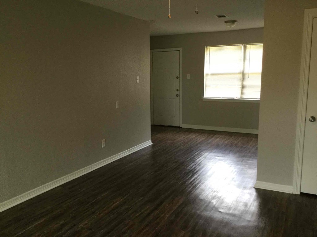 an empty living room with wood floors and a window