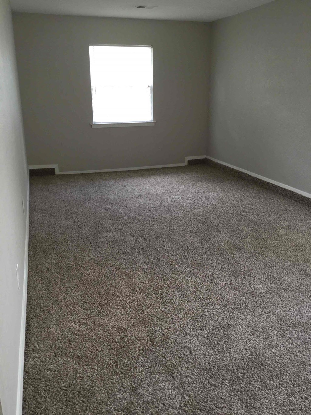 an empty room with a carpeted floor and a window