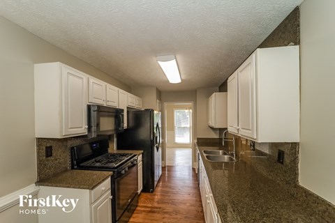 a kitchen with white cabinets and granite counter tops and black appliances