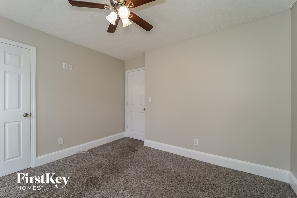 the upstairs bedroom has a ceiling fan and a door to the bathroom