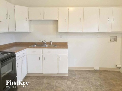 A kitchen with white cabinets and a black stove top oven.