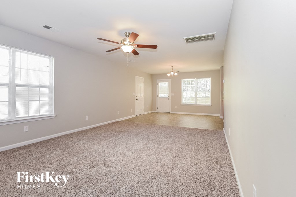 A spacious room with a ceiling fan and carpeted floor.