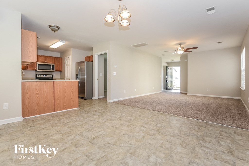 A spacious living room with a kitchen area in the background.