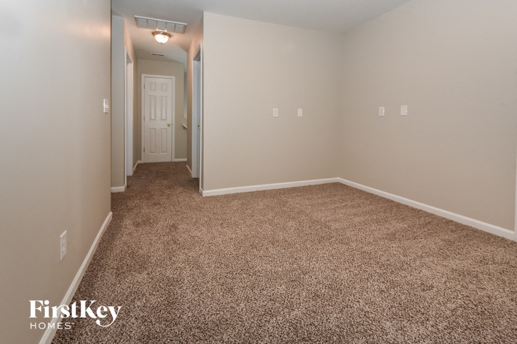 A carpeted room with a doorway leading to another room.