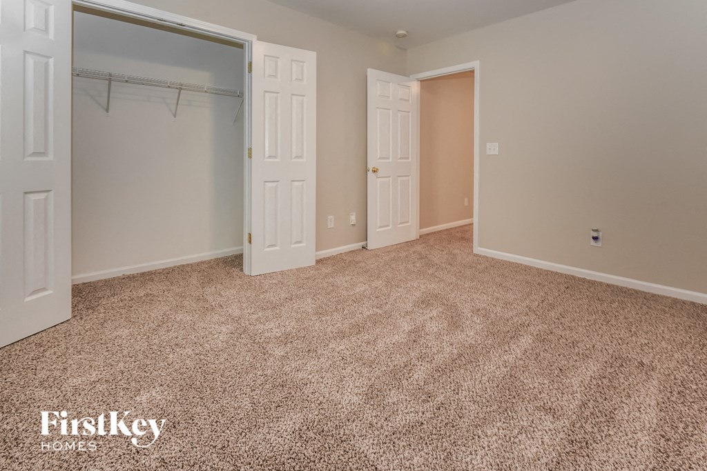 A bedroom with a carpeted floor and two doors.