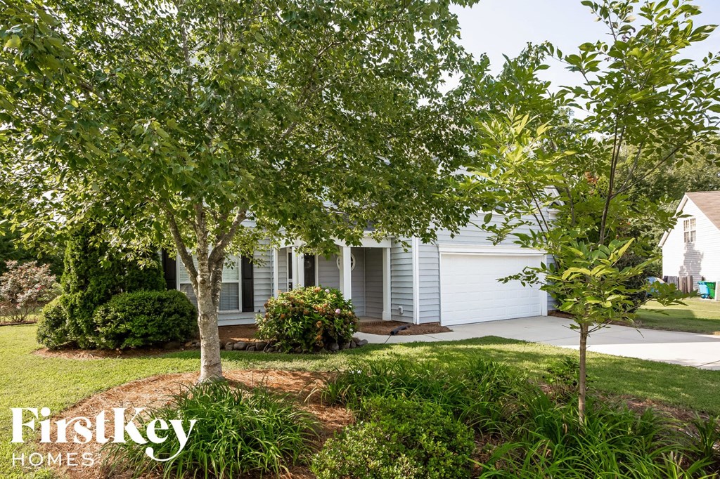 A white house with a tree in front of it.