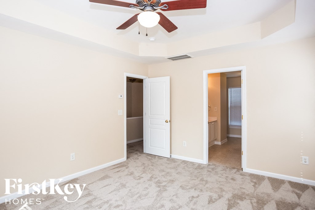 A room with a fan and a carpeted floor.