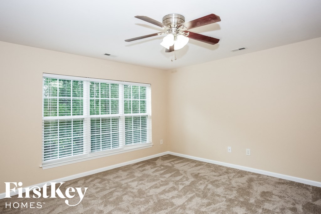 A room with a fan and a window with blinds.