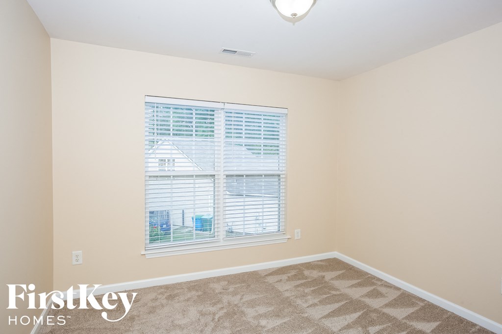 A room with a carpeted floor and a window with blinds.