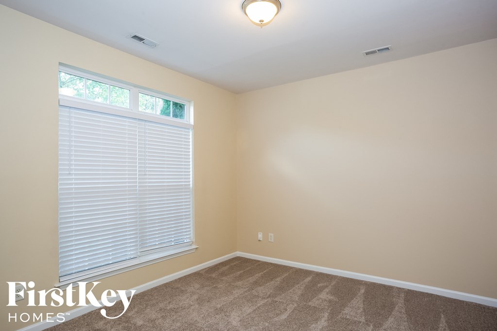 A room with a carpeted floor and a window with blinds.