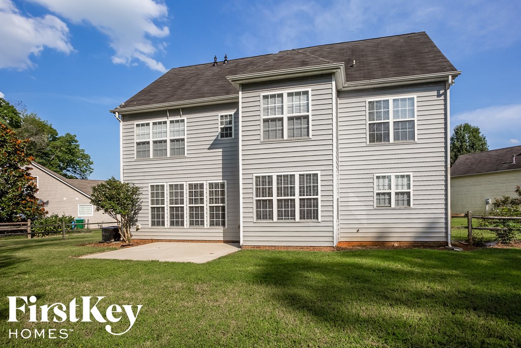 A grey two-story house with a large front yard.