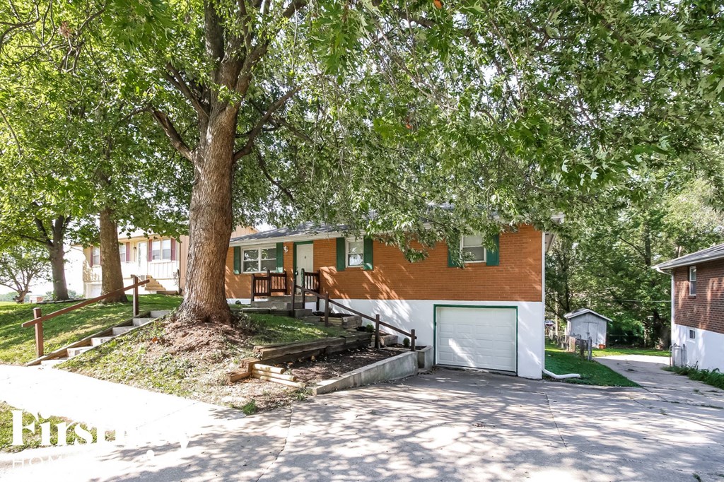 a house with a tree in front of it and a driveway