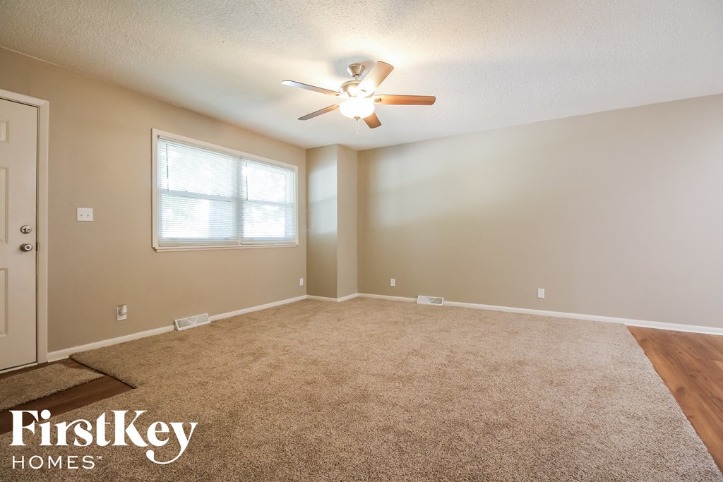 the spacious living room with carpeting and a ceiling fan