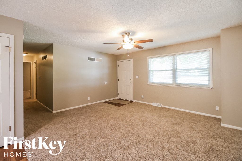 the spacious living room with carpeting and a ceiling fan