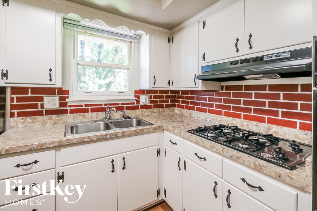 a kitchen with white cabinets and a counter top and a sink