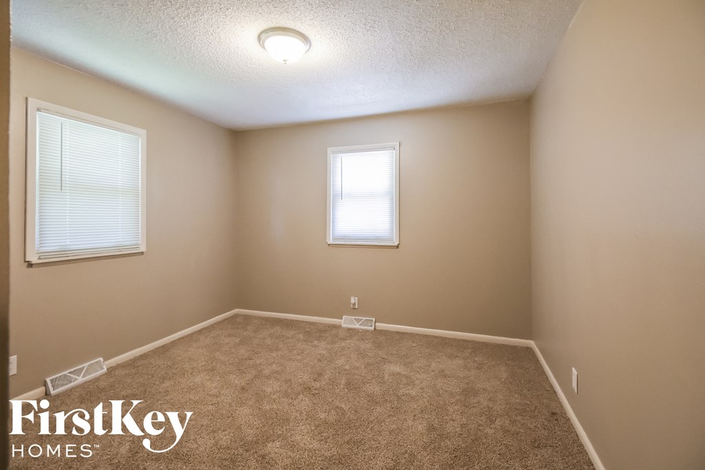 a empty room with a carpeted floor and two windows