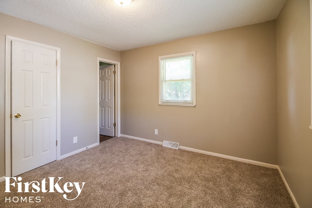 a carpeted room with a white door and a window