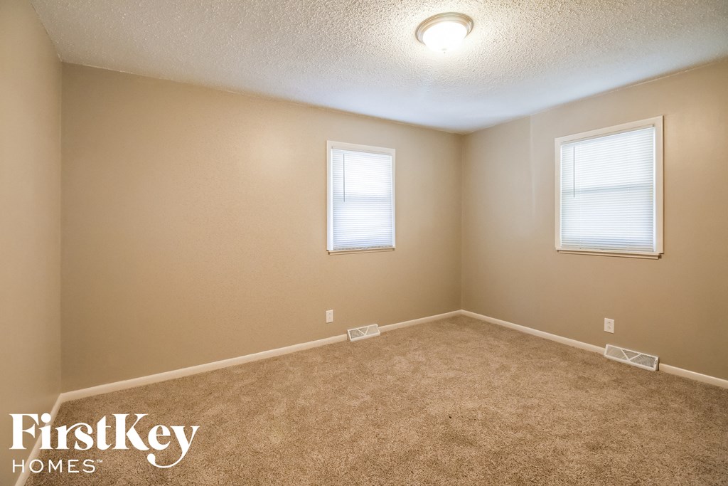 a bedroom with a carpeted floor and two windows