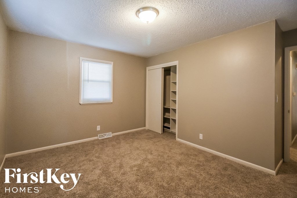 a carpeted room with a closet and a window
