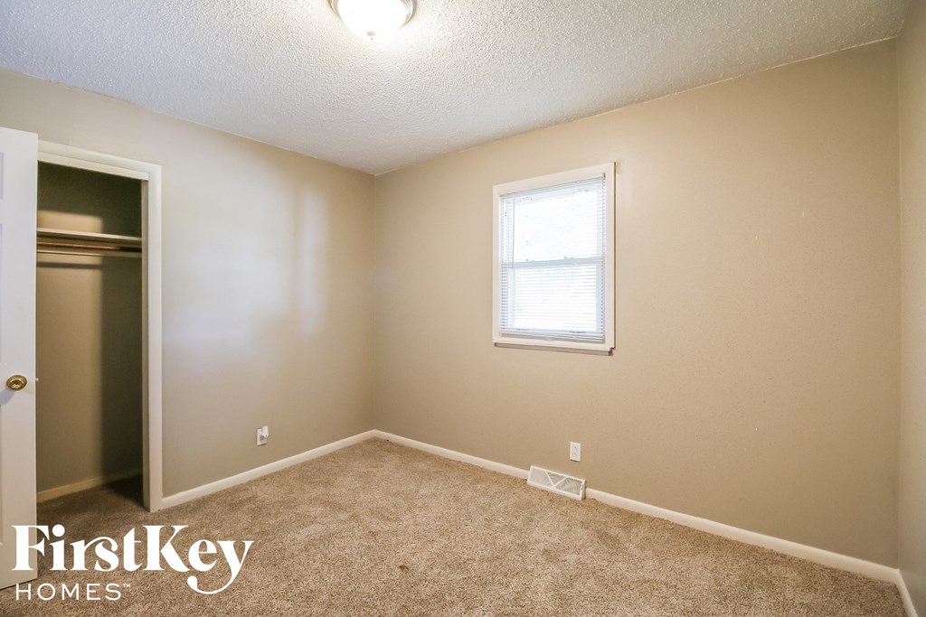 a bedroom with a closet and a window and a carpeted floor