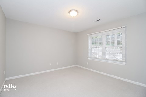 a bedroom with a large window and white walls