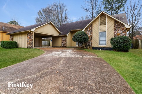A house with a stone wall and a brown roof is for sale.