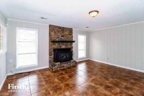 A room with a stone fireplace and tile flooring.