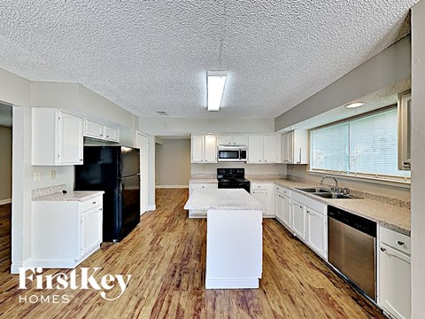 A kitchen with wooden floors and white cabinets.
