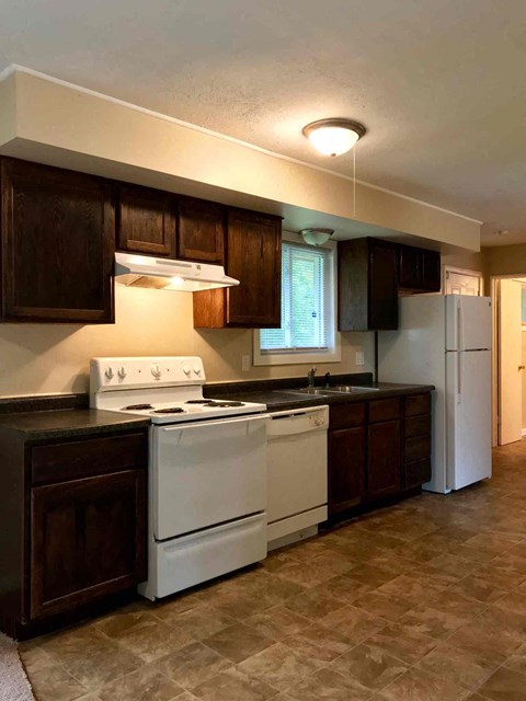 A kitchen with white appliances and brown cabinets.
