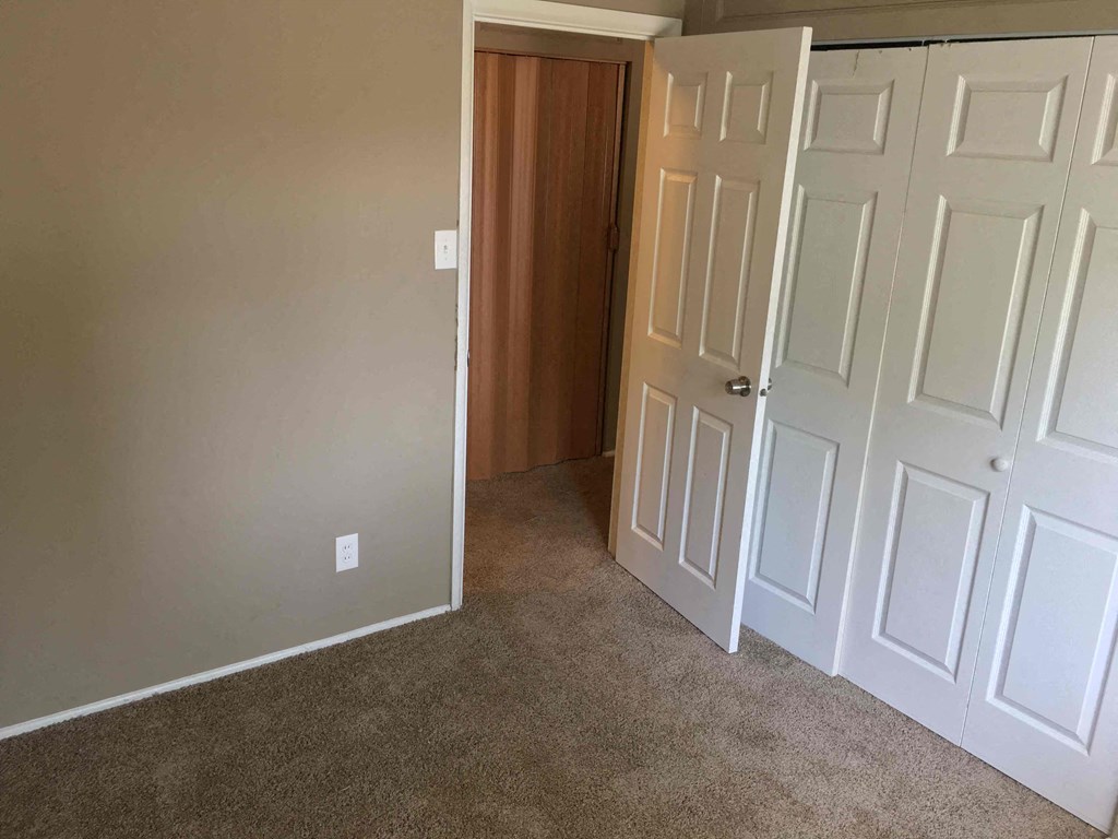 A room with a brown door and white walls.
