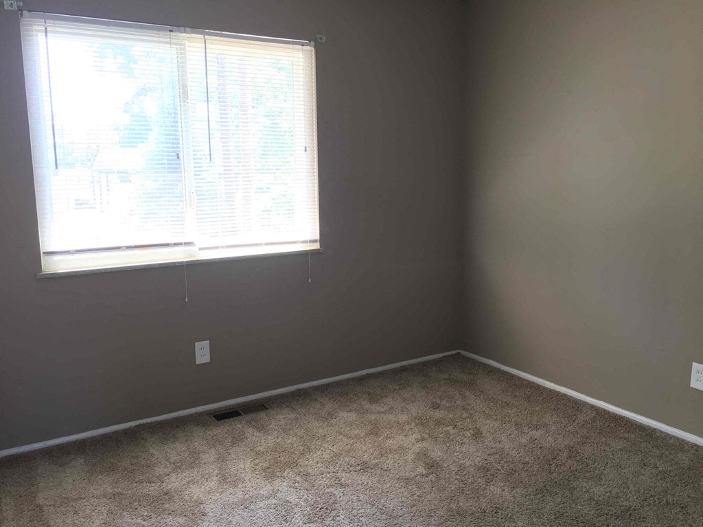 A room with a window and carpeted floor.