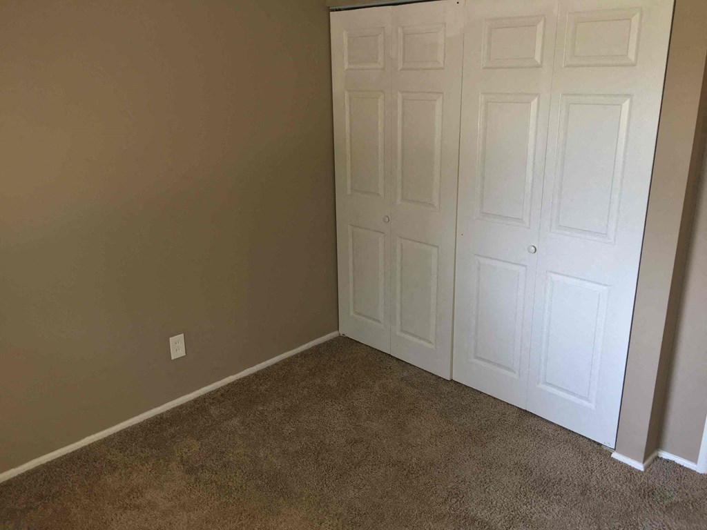 A white door is in a room with carpeted floor.