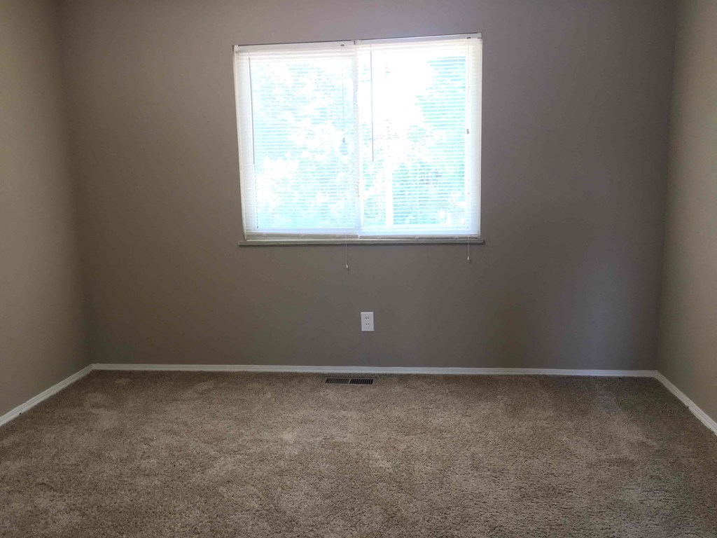 A room with a carpeted floor and a window.