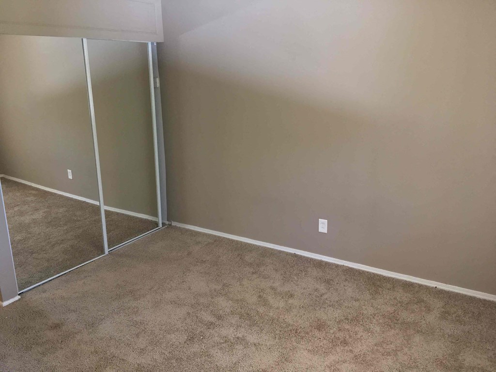 A room with a carpeted floor and a wall-mounted light switch.