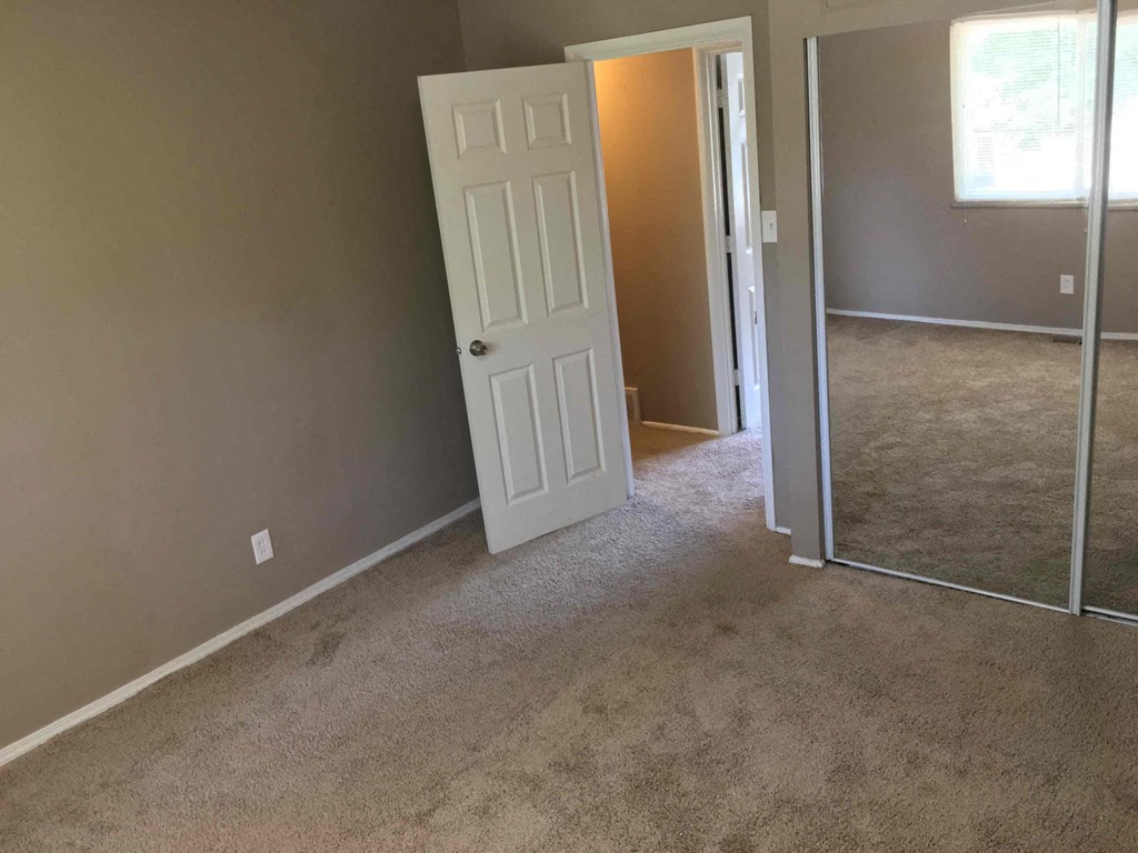 A room with a white door and carpeted floor.