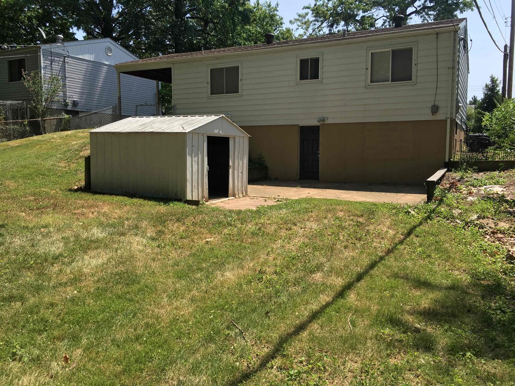 A shed sits in a grassy yard in front of a house.