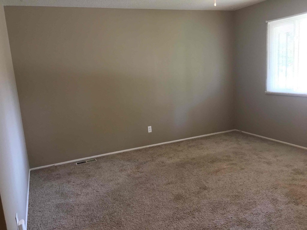 A room with carpeted floor and a window.