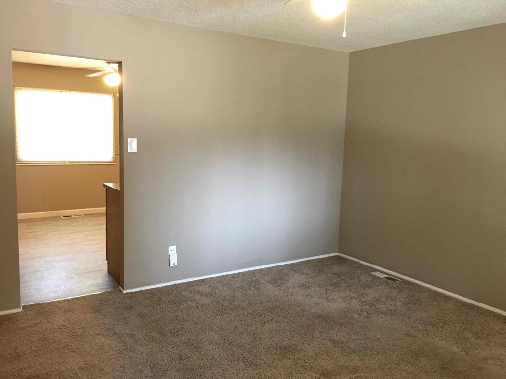 A room with a carpeted floor and a door leading to another room.