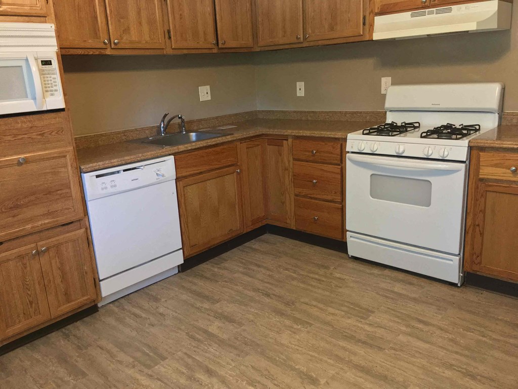 A kitchen with a white stove and wooden cabinets.