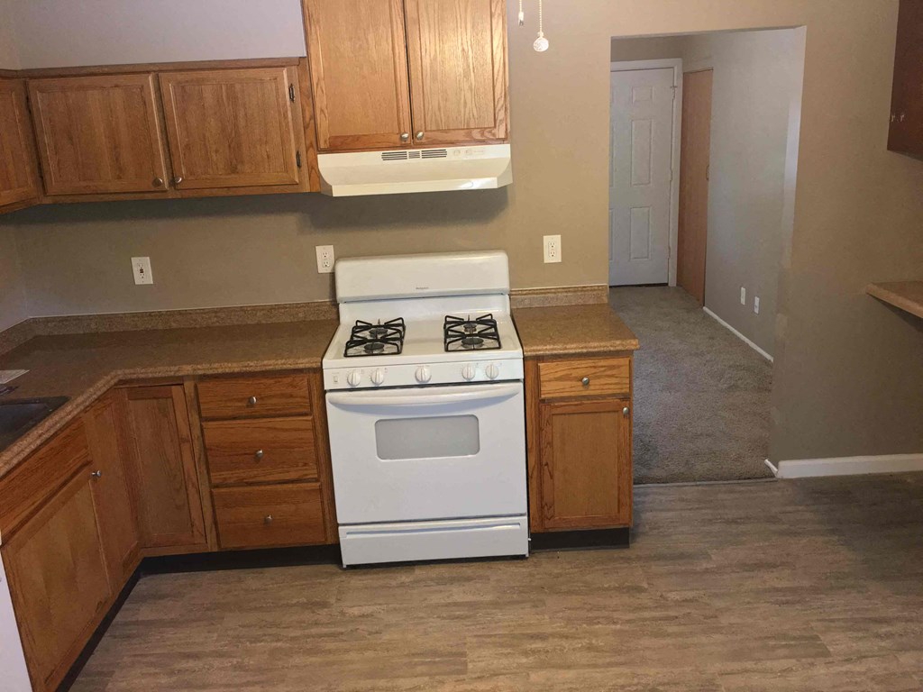A white stove is in a kitchen with wooden cabinets.