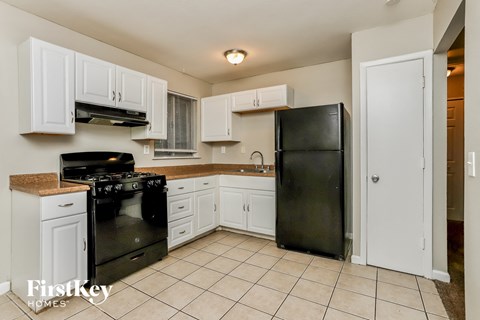 A kitchen with white cabinets and black appliances.