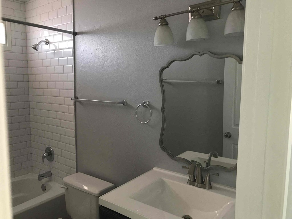 A bathroom with a white toilet, sink, and a white bathtub.
