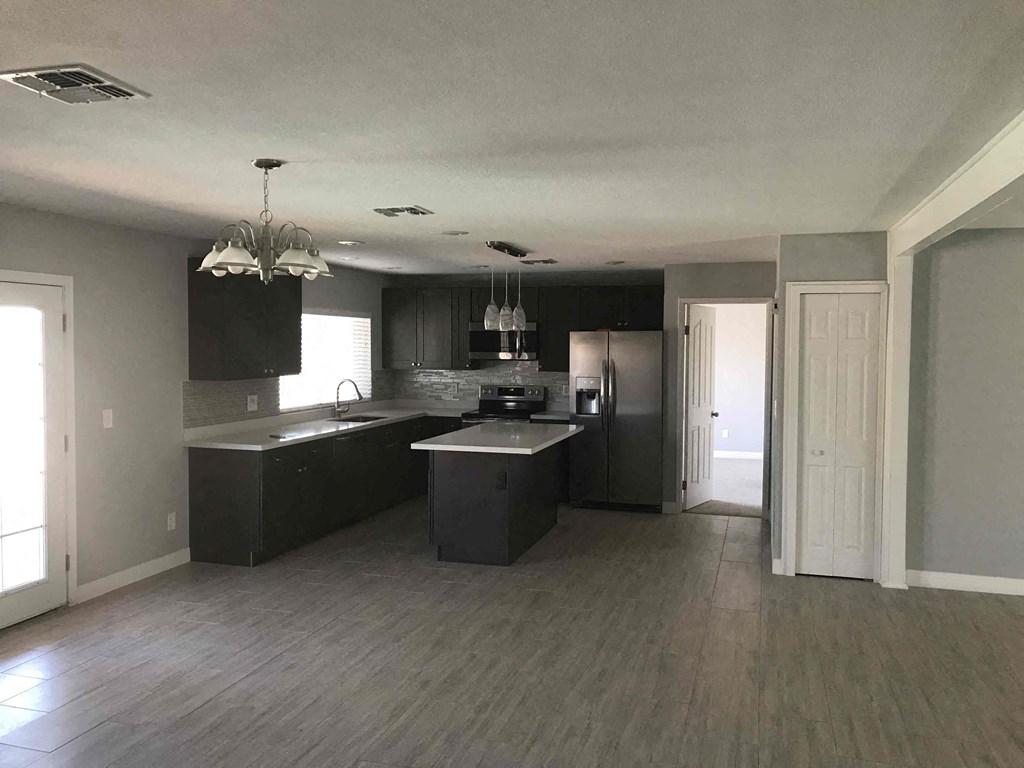 A modern kitchen with a large island and stainless steel appliances.
