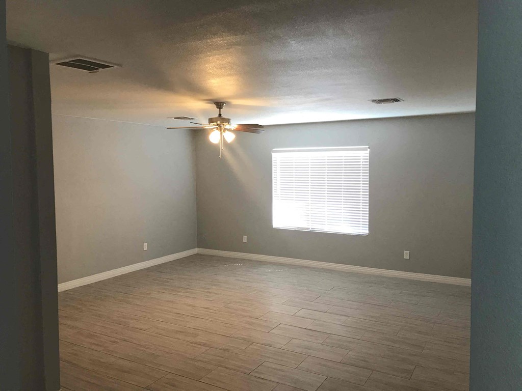 A room with a ceiling fan and a window with blinds.