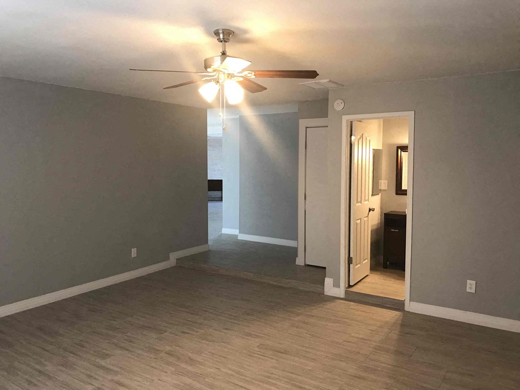 A room with a ceiling fan and a doorway leading to another room.