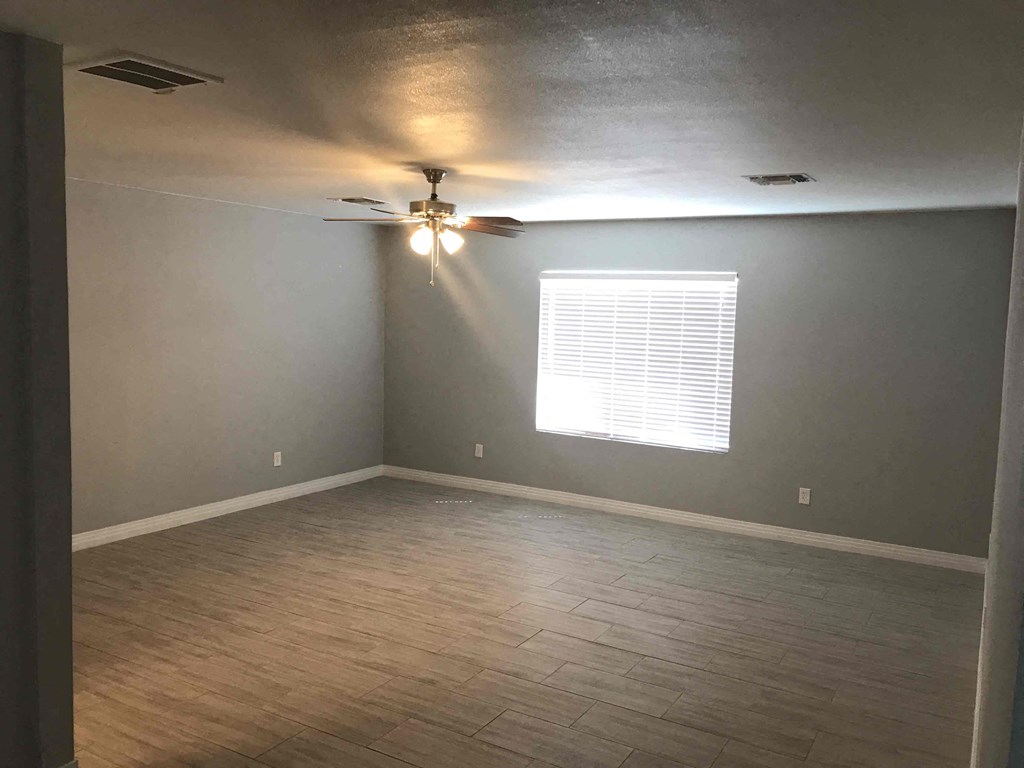 A room with a ceiling fan and a window with blinds.