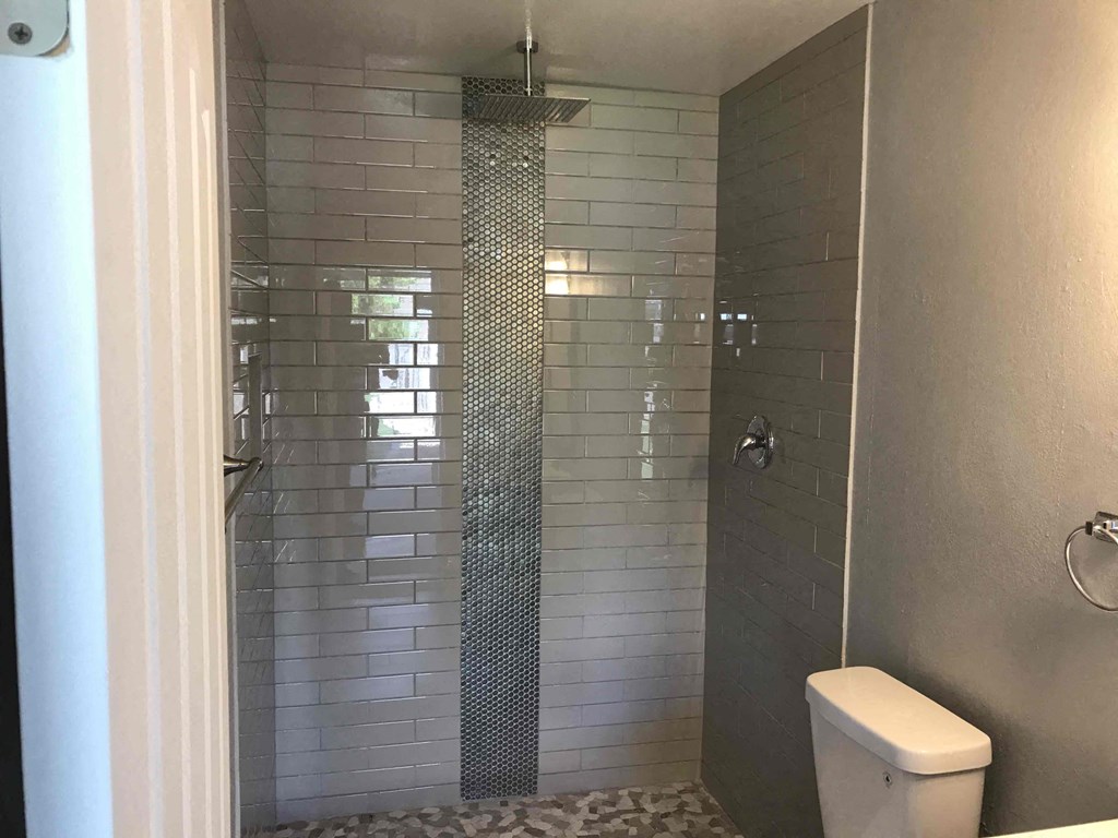 A white toilet sits next to a glass block shower.