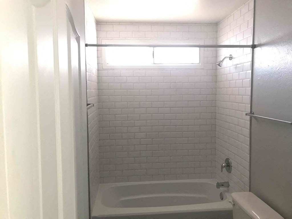 A white bathroom with a tub and a toilet.